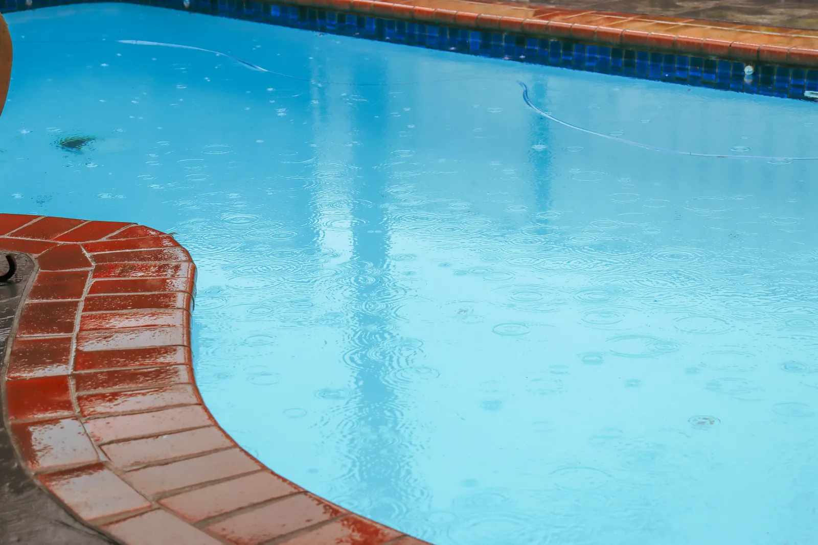 Rain falling on a backyard pool